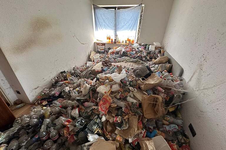 messi-v-12-min Ein kleiner, unordentlicher Raum mit Stapeln von Plastikflaschen, Tüten und diversem Müll, der den Boden bedeckt - Notfall-Hilfe: Messie Wohnung Entrümpelung.